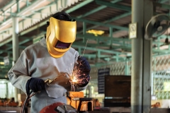 A craftman is welding with workpiece steel.Working person About welder steel Using electric welding machine There are lines of light coming out and safety equipment in factory industry.